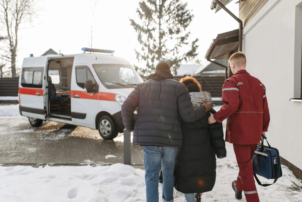 Paramedics guide a family to an ambulance during winter, showcasing emergency medical care.